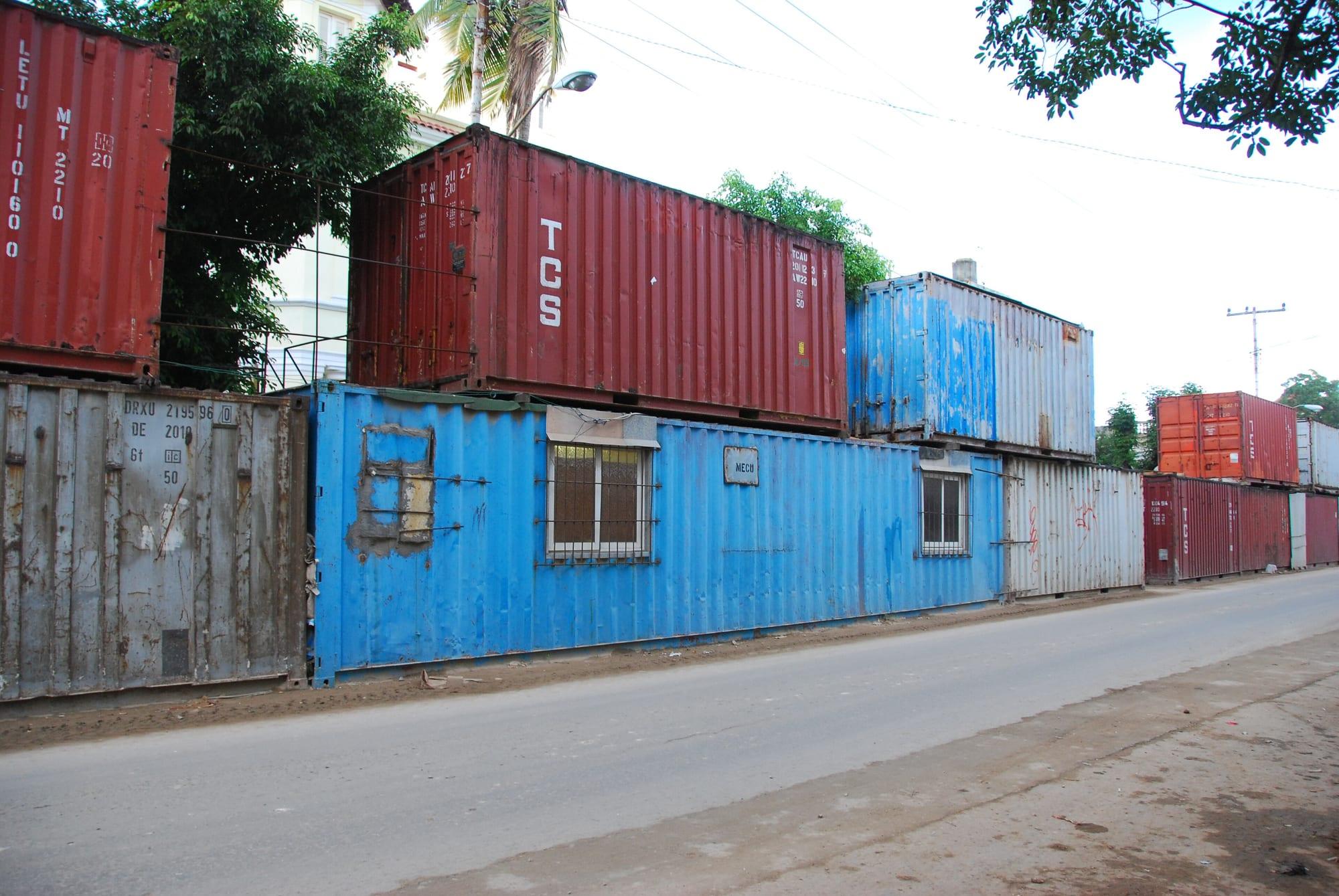 A row of old shipping containers fitted with windows and doors as homes beside a street in Havana