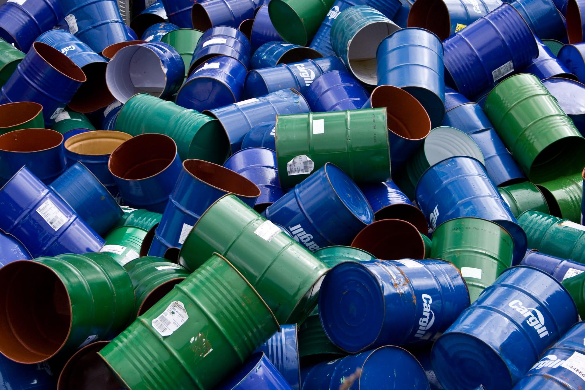 A heap of empty blue and green steel drums dumped together