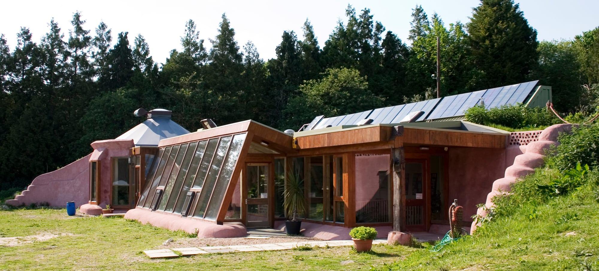 The glazed front of Earthship Brighton, a building with earth-filled tyre walls and solar panels